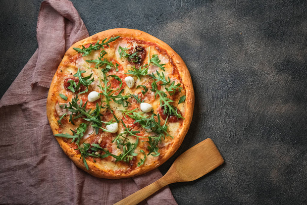 Pizza italienne traditionnelle avec jambon, champignons, roquette, mozzarella, basilic et tomates sur fond sombre vue du dessus copier l'espace
. - Photo, image