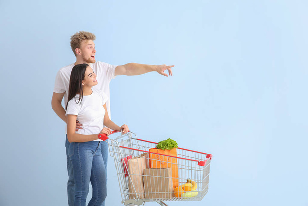 Paar mit Warenkorb auf farbigem Hintergrund - Foto, Bild