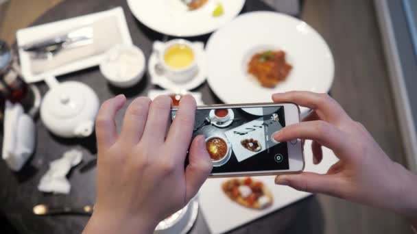 Woman takes pictures of food on the phone in a cafe - Footage, Video