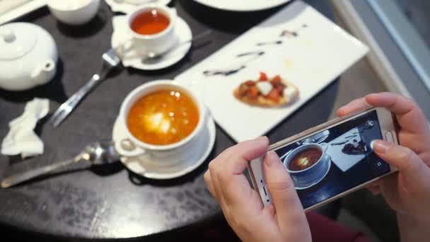 Kobieta robi zdjęcia jedzenia przez telefon w kawiarni. - Materiał filmowy, wideo