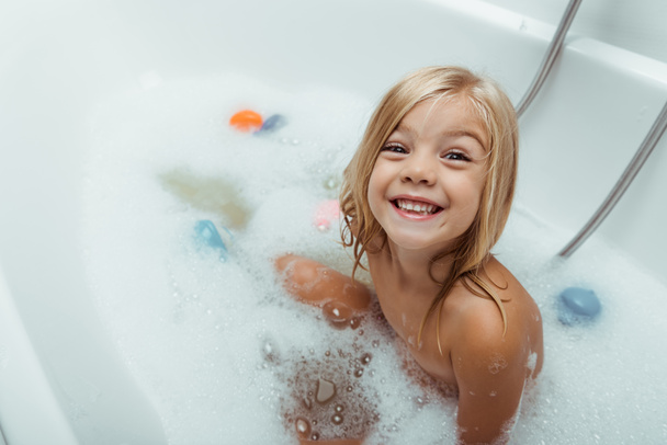 happy naked child taking bath with bath foam at home  - Foto, Bild