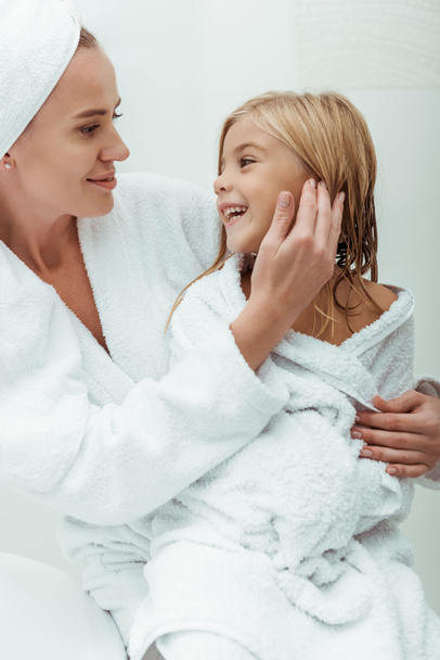 happy mother touching face of cute daughter in bathroom  - Foto, Imagem