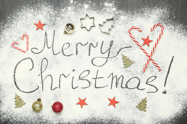 Κείμενο Καλά Χριστούγεννα σε αλεύρι με στολίδια και καραμέλες - Φωτογραφία, εικόνα