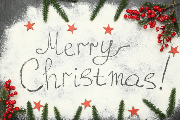 Text Merry Christmas on flour with fir tree branches and red berries - Foto, imagen