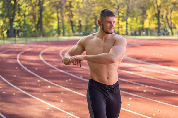 Männermodel mit muskulöser Passform und schlankem Körper im Stadtstadion.  - Foto, Bild