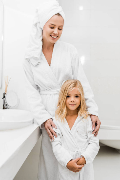 wesoła matka w ręczniku patrząc na cute córka w łazience  - Zdjęcie, obraz