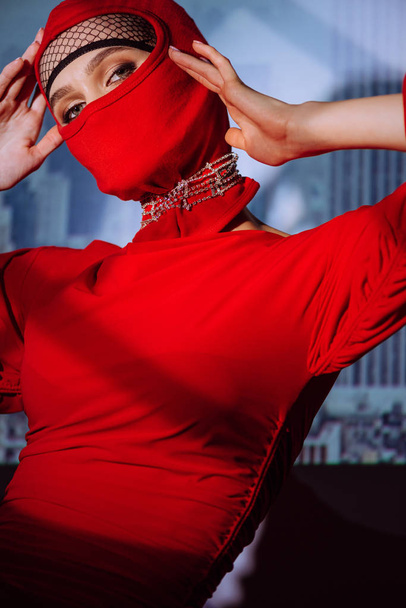 стильная женщина в красном платье и балаклаве на фоне города
  - Фото, изображение