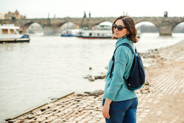 Молодая женщина наслаждается прекрасным видом на Прагу. Счастливая девушка с рюкзаком в отпуске
 - Фото, изображение