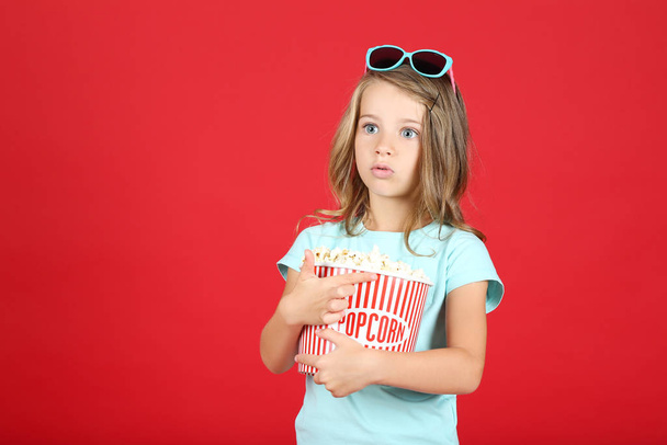 Young girl with popcorn in bucket on red background - Photo, Image