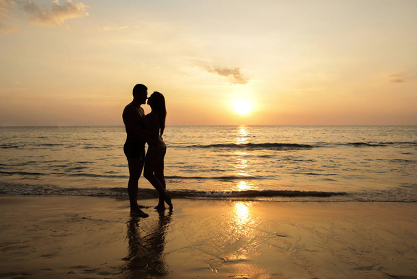 Imagen tonificada roja de una pareja en una playa tropical al atardecer
 - Foto, imagen