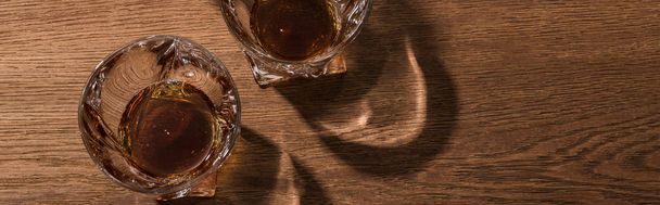 Верхний вид коньяка в стаканах на деревянный стол, панорамный снимок
 - Фото, изображение