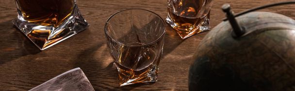 Focus selettivo di brandy in bicchieri con globo e mappa su tavolo in legno, scatto panoramico
 - Foto, immagini