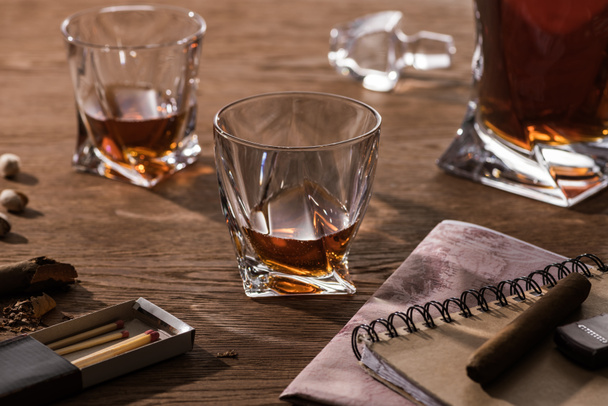 Glasses of brandy, cigars with map and pistachios on wooden table - 写真・画像
