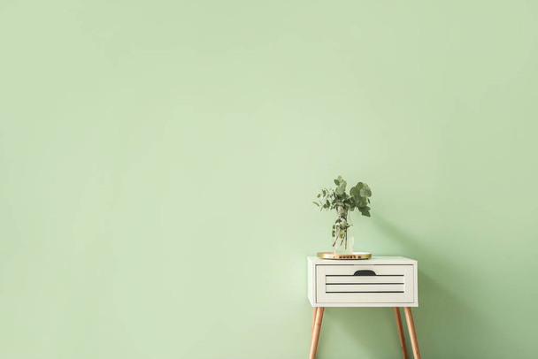 stilvoller Tisch mit Eukalyptuszweigen in Vase auf farbigem Hintergrund - Foto, Bild
