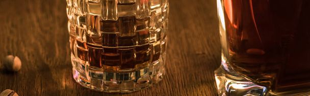 Glas cognac met karaf en pistachenoten op houten tafel, panoramisch schot - Foto, afbeelding