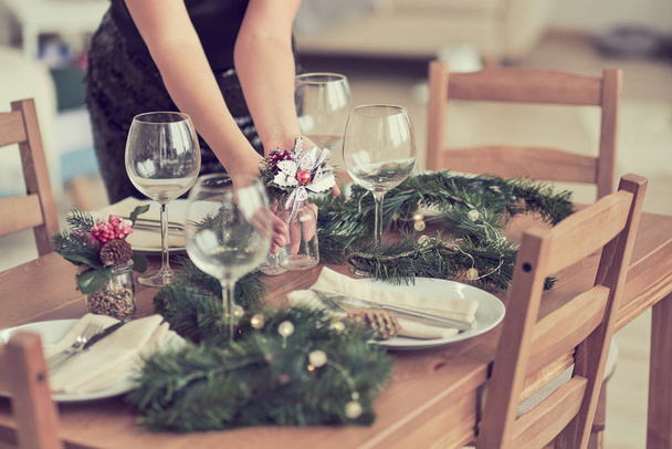 De vrouw wacht op de gasten en dekt de tafel. Feestelijke ligtafel, voorbereiding voor kerstdiner. - Foto, afbeelding