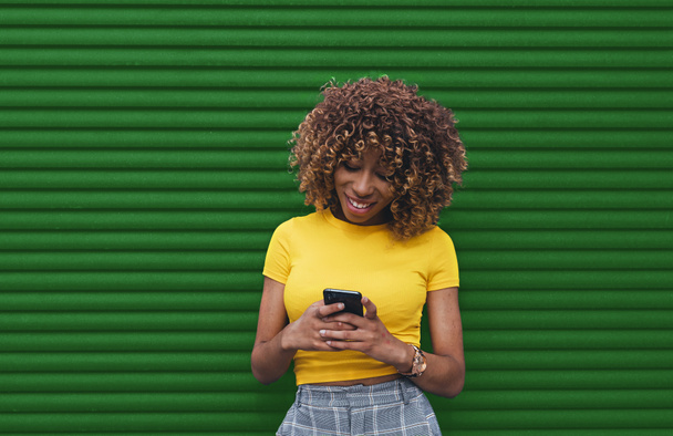 Jeune femme en blouse jaune tenant de téléphone avec les deux mains - Photo, image