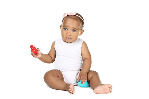 American baby girl sitting and playing with toys on white background - Foto, Bild