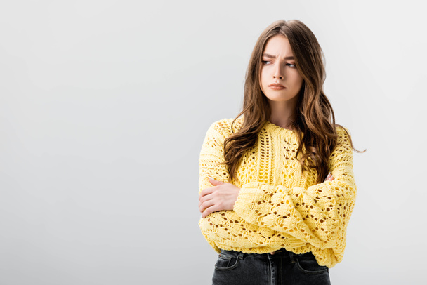 offended girl in yellow sweater standing with crossed arms isolated on grey - Фото, изображение