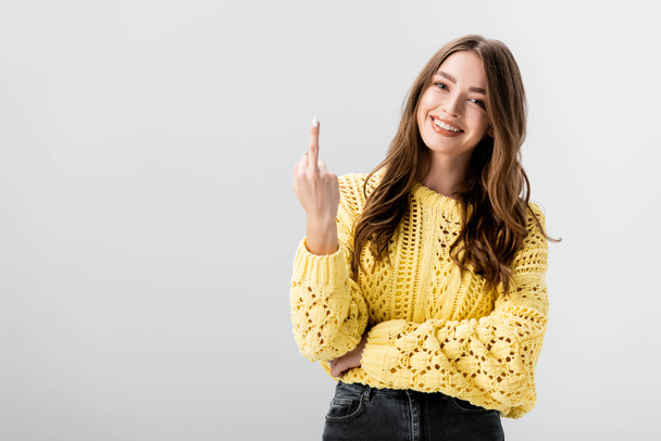cheerful girl looking at camera while showing middle finger isolated on grey - Photo, Image
