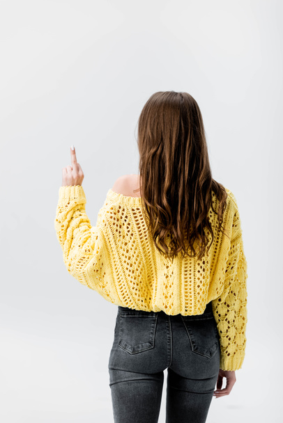 visszapillantás a lány sárga pulóver mutatja középső ujját elszigetelt szürke - Fotó, kép