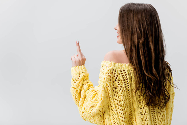 back view of girl in yellow sweater showing middle finger isolated on grey - Foto, imagen