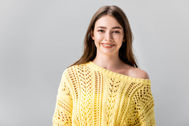 vonzó lány sárga pulóverben mosolyog kamera elszigetelt szürke - Fotó, kép