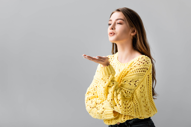 pretty girl in yellow sweater showing blowing kiss isolated on grey - Фото, изображение