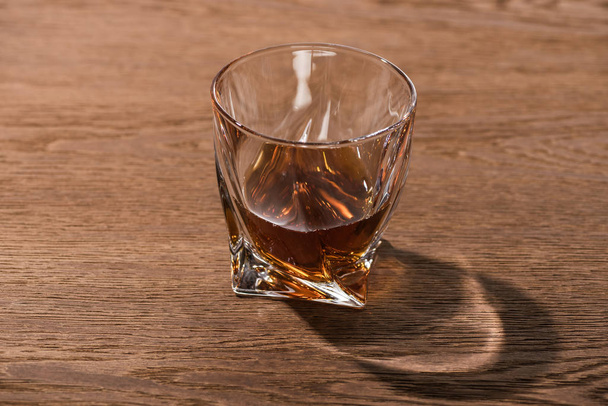 Glass of brandy with shadow on wooden table - Foto, Imagem