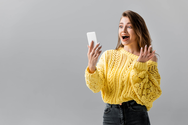 surprised girl showing wow gesture during video chat on smartphone isolated on grey - Fotografie, Obrázek