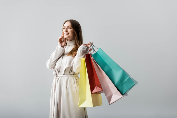 trendy girl looking away while holding shopping bags isolated on grey - Fotografie, Obrázek