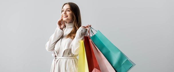 panoramic shot of stylish girl looking away while holding shopping bags isolated on grey - Photo, Image