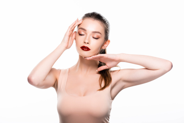 atraente jovem mulher tocando o rosto com os olhos fechados isolados no branco
 - Foto, Imagem