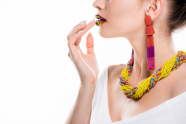 partial view of girl in beaded necklace and earrings touching beads on lips isolated on white - Photo, Image