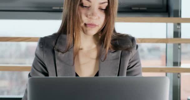Concerned woman working on laptop computer and looking away thinking solving problem at office. Serious attractive female working with notebook - Metraje, vídeo