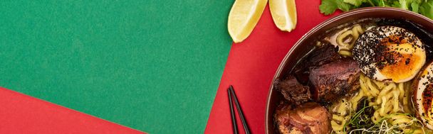 緑と赤の表面に新鮮な食材と箸のそばのスパイシーな肉ラーメンのトップビュー,パノラマショット - 写真・画像