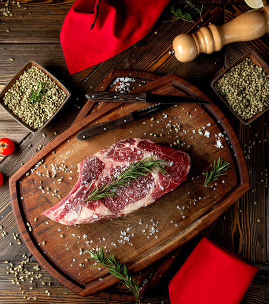 raw meat slice topped with herbs and salt - Фото, зображення
