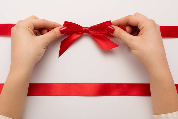 cropped view of woman touching red bow on white  - Photo, Image