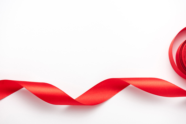top view of curled and red ribbon on white with copy space  - Fotó, kép