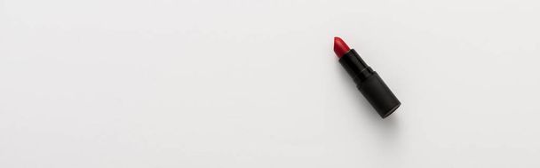 panoramiczne ujęcie czarnej tuby z czerwoną szminką na białym z przestrzenią do kopiowania  - Zdjęcie, obraz