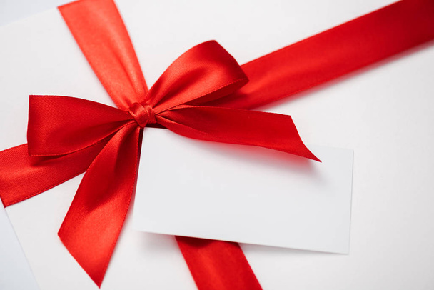 blank card near red ribbon with satin bow on white  - Фото, зображення
