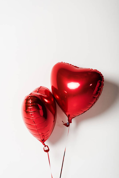 červené a lesklé srdce ve tvaru balónky na bílém s kopírovacím prostorem  - Fotografie, Obrázek
