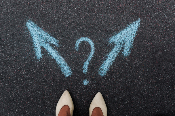 top view of woman standing near blue directional arrows and question mark on asphalt  - Photo, Image