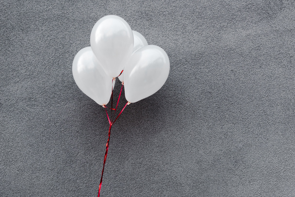 witte en decoratieve ballonnen op grijs met kopieerruimte  - Foto, afbeelding