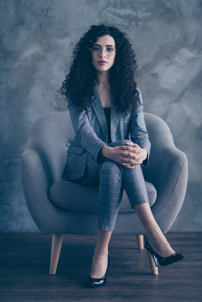 Vertical view portrait of her she nice attractive pretty classy chic content serious wavy-haired girl shark sitting in chair crossed legs job seeker attending meeting gray concrete wall background - Foto, imagen