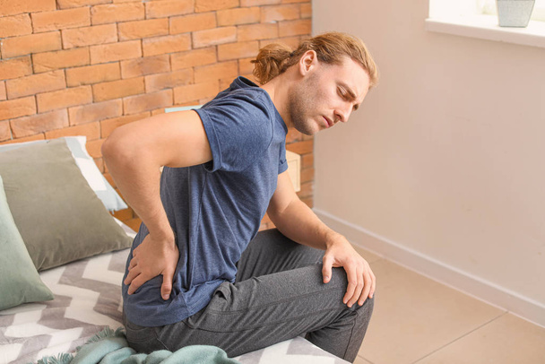 Молодой человек страдает от болей в спине дома - Фото, изображение