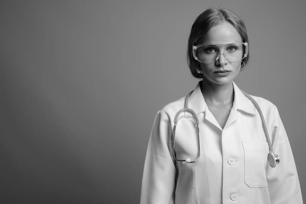 Young beautiful woman doctor as scientist wearing protective glasses in black and white - 写真・画像