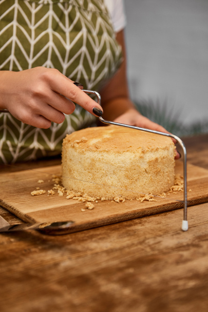 Cropped view of confectioner cutting cake with cake slicer  - Photo, Image