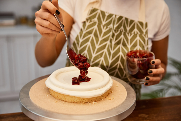 Cropped view of confectioner putting berry jam on cake - Foto, Imagem