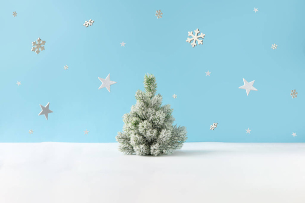 Creative layout with snowy Christmas tree and stars with snowflakes on bright blue background. Minimal winter nature holiday scene.  - Photo, Image